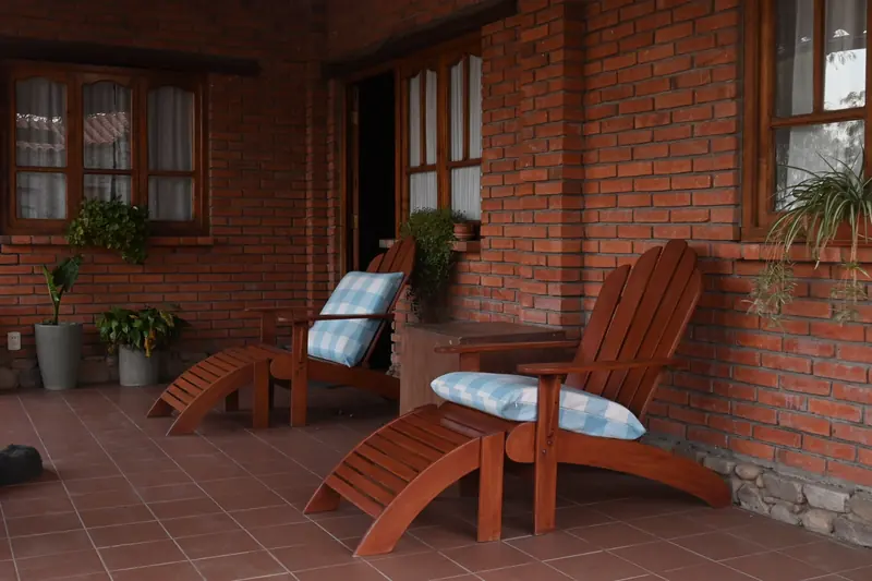Galería de la Cabaña 1 con dos reposeras de madera y plantas