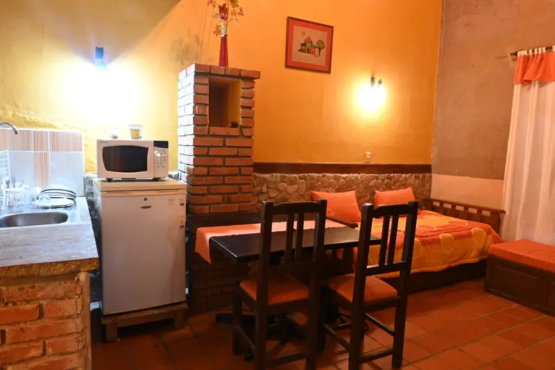 Kitchenette con microondas y frigobar, y mesa con dos sillas en la Cabaña 10