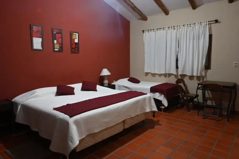 Dormitorio de la Cabaña 3 con dos camas, escritorio y vigas de madera