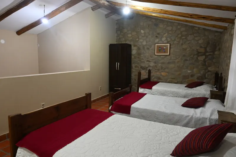 Planta alta de la Cabaña 4 con tres camas simples y vigas de madera