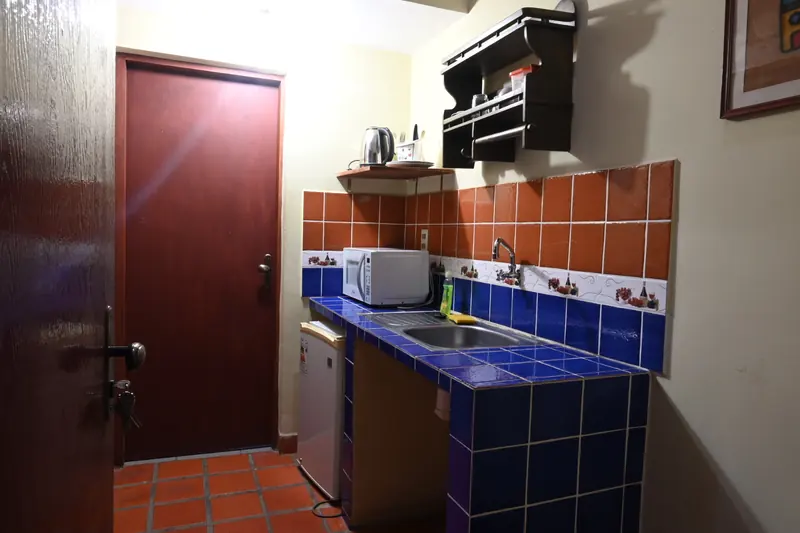 Kitchenette con azulejos azules, microondas y frigobar en la Cabaña 5