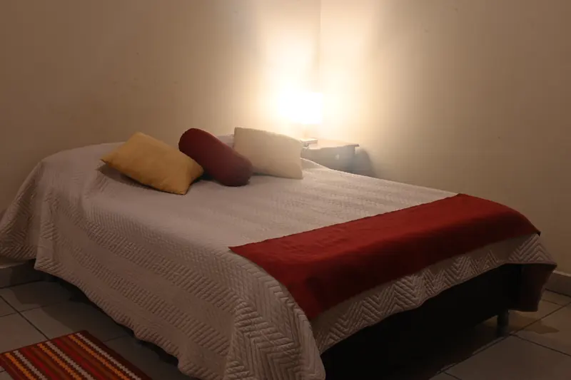 Cama doble con cojines y luz cálida en la Cabaña 6