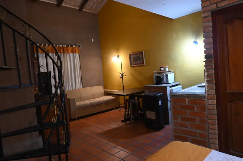 Estar de la Cabaña 9 con escalera caracol, sofá y kitchenette