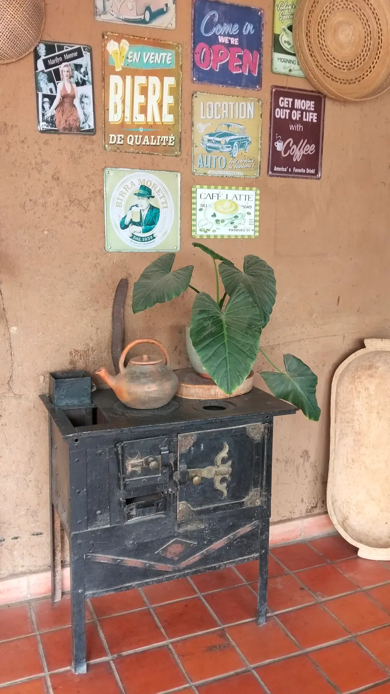 Antigua cocina de hierro con tetera, carteles de época y plantas