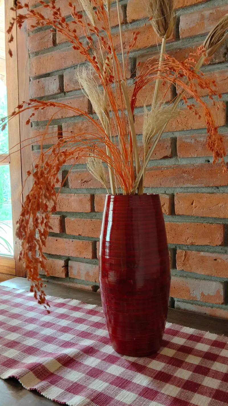 Florero rojo con espigas secas sobre un mantel a cuadros