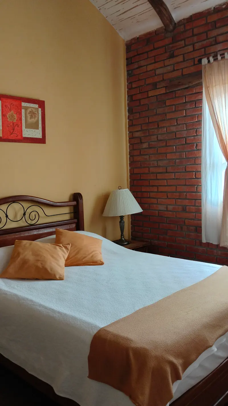 Dormitorio con cama doble y cojines naranjas