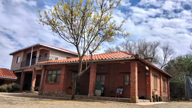 Cabañas con galería bajo un árbol florido en El Cadillar, Tarija