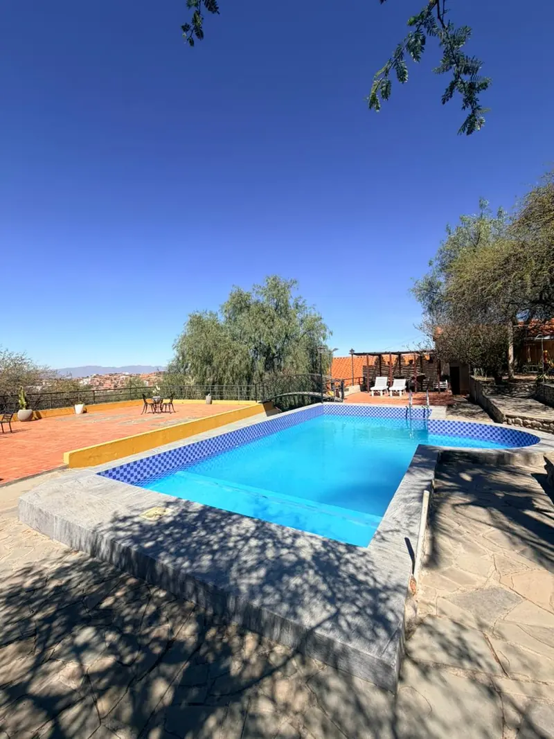 Piscina con la sombra de los árboles sobre el solado de piedra