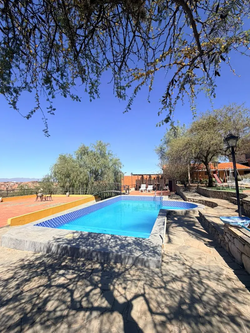 Piscina al aire libre de El Cadillar en un día de sol, con el valle de Tarija de fondo